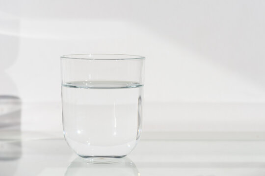 Vaso de cristal transparente lleno de agua sobre fondo blanco.
