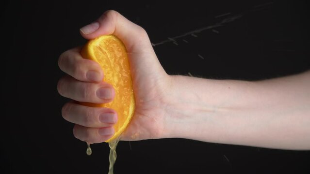 Close-up of female hand squeezing an orange. Person pressing a juicy fruit without a juicer. High quality 4k footage