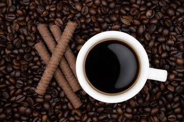 White cup with coffee on the background of coffee beans. Delicious chocolate cookies. top view