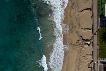 Fototapeta na wymiar Aerial view of ocean waves breaking on a sandy beach. Beach erosion after coastal flooding.