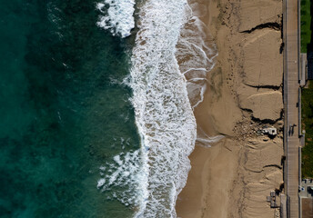 Aerial view of ocean waves breaking on a sandy beach. Beach erosion after coastal flooding.