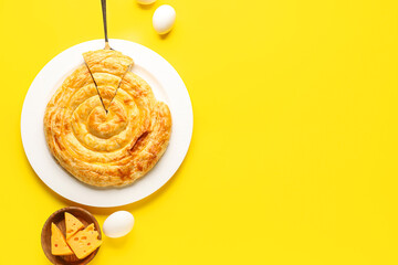 Plate with delicious cheese pie and eggs on yellow background