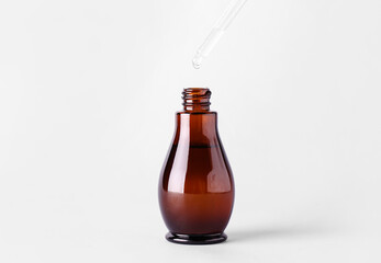 Dripping of serum into bottle on light background