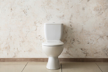 Ceramic toilet bowl near light wall