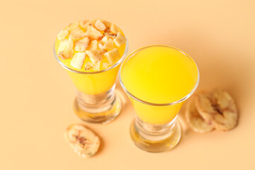 Shots of delicious pudding with dried banana slices on beige background