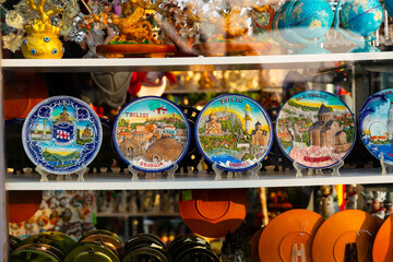 Various colorful hand-painted ceramic plates depicting tourist attractions on showcase of Georgian...
