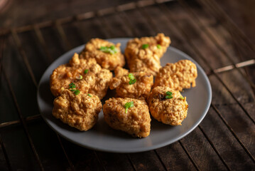 Pieces of flour-fried cauliflower with vegan sauces on a plate on a dark background. Cauliflower wings food.