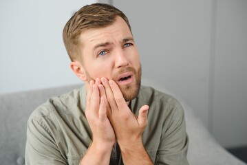 Dental health problems concept. Man suffering from strong toothache. Upset male patient with...