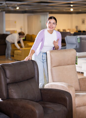 Naklejka premium young girl seller in furniture store offers to buy stylish home furniture