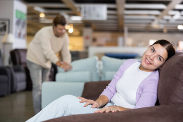 Woman trying out armchair in furniture showroom