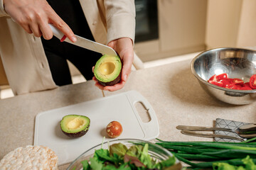 Close up of woman hands cutting fresh avocado in modern kitchen. Nutrition And Diet. Healthy food concept. Ingredients for smoothies