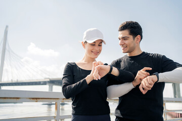 Runners are a man and a woman couple with a fitness smartwatch app and running time reconciliation with health tracking technology. 