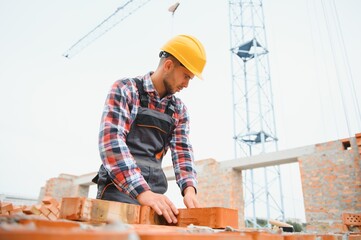 Yellow colored hard hat. Young man working in uniform at construction at daytime.