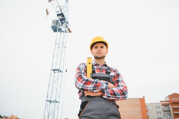 Communicating with crane guy. Construction worker in uniform and safety equipment have job on building.