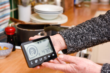 The woman checks the smart meter to see weekly cost of electricity to power appliances and cook food