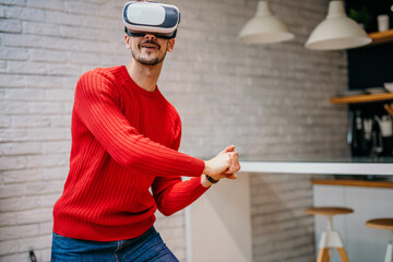 Caucasian man wearing headset glasses of virtual reality gesticulating swing with hand while...