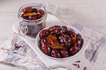 Preserving pickled plums in its own juice and seasonings on a wooden table. Healthy fermented food. Home canned vegetables.