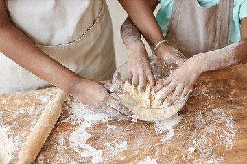 Mother and daughter kneading dough together baking homemade pastry