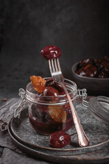 Bowl of pickled plums with spices on rustic wooden background. Clean eating, vegetarian food concept