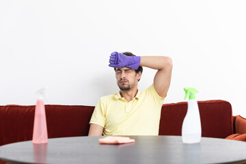 Tired and stressed man sits and complains after exhausting cleaning. Household concept	
