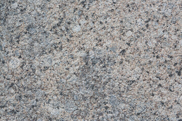 Granite texture. Natural gray granite with a grainy pattern. Stone background. Solid rough surface of rock. Durable construction and decoration material. Close-up.