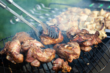 Cooking different meat on barbecue. Grilled and roasted lamb steaks on bbq. Take one piece with grill tongs