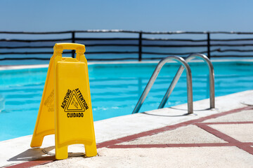 Wet floor warning sign near a swimming pool at poolside