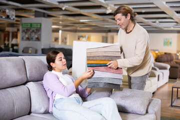 couple of Europeans choose upholstery for upholstered furniture for home in furniture store