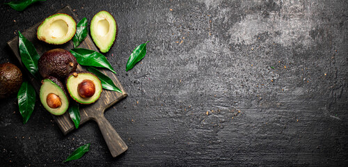 Fresh avocado with foliage on a cutting board.