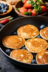 Pancakes in a frying pan with fresh berries. 