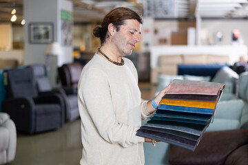 Middle-aged man choosing colors of furniture for interior his house