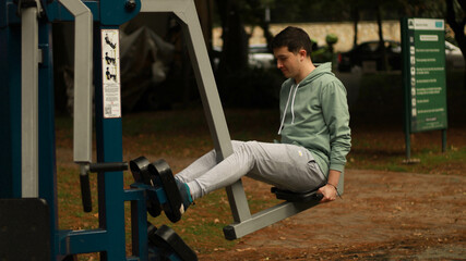 Fototapeta na wymiar young man exercising in the park athlete exercising on machine 