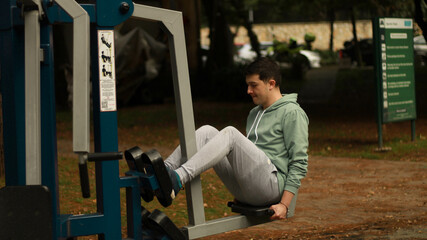 Fototapeta na wymiar young man exercising in the park athlete exercising on machine 
