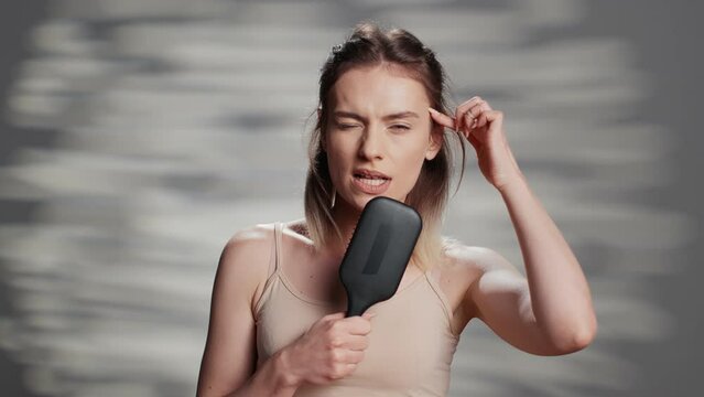 Positive confident person holding hair brush to sing, having fun in studio to advertise self acceptance and skincare ad campaign. Young woman with bare glowing skin promoting imperfections.