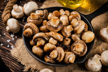 Fototapeta na wymiar Frying pan with fried mushrooms on a wooden tray. 