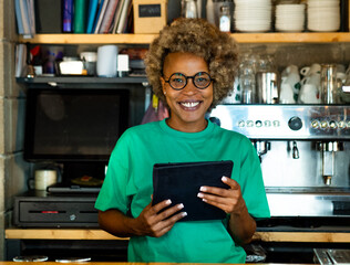 Portrait of a young African American woman wih a tablet looking at camera in a pub. Entrepreneurial woman, small business