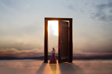 woman looking at the wonderful landscape on the doorstep of a surreal door - obrazy, fototapety, plakaty