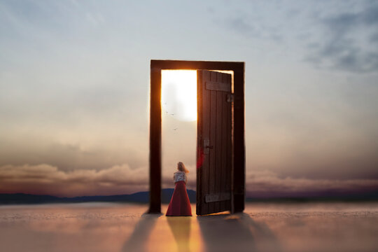 woman looking at the wonderful landscape on the doorstep of a surreal door