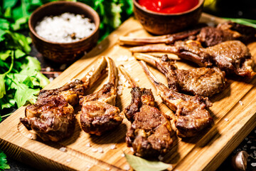 Grilled rack of lamb on a cutting board with parsley and tomato sauce. 