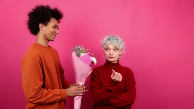 Close-up view of attractive girl rejecting beautiful bouquet from a young guy. Portrait of annoyed woman looking angry and mad as she sees her friend. High quality 4k footage