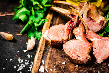 Rack of grilled lamb on a wooden cutting board with parsley. 