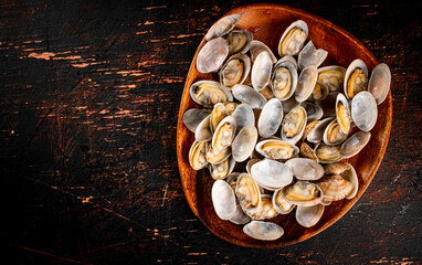 A wooden plate full of fresh vongole. 