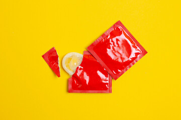 torn pack of a condom lies on a yellow background, the concept of safe sex