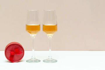 Two bubbly champagne glasses and red box as gift on white background with copy space. Valentines day, love, birthday concept