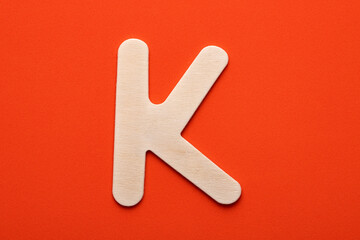White wooden capital letter K on orange foamy background
