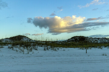 Cloud at sunset over sand dunes.