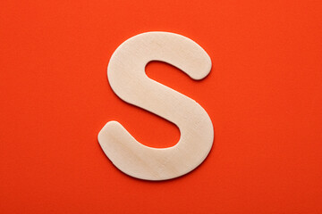 White wooden capital letter S on orange foamy background