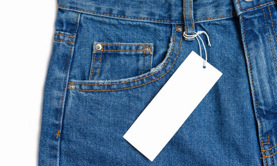 Front side pocket and price tag of blue jeans pants close-up isolated on white background, mockup. Fashion concept, business, shopping, sale. Design detail, button and seams, clothing tag, copy space