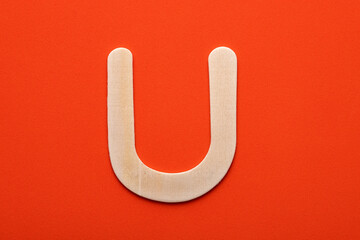 White wooden capital letter U on orange foamy background