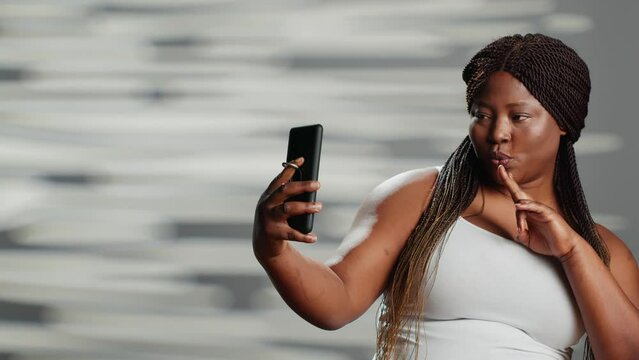 African american woman posing on smartphone camera, acting silly and showing body confidence. Happy beautiful girl being sensual and natural, expressing self body acceptance.